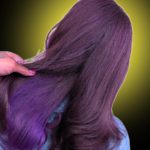 Rear view of a person with long, straight deep plum-purple hair featuring a hidden vibrant violet-purple layer being lifted by a hand.